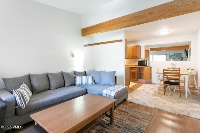 living room featuring beam ceiling and light wood-style flooring