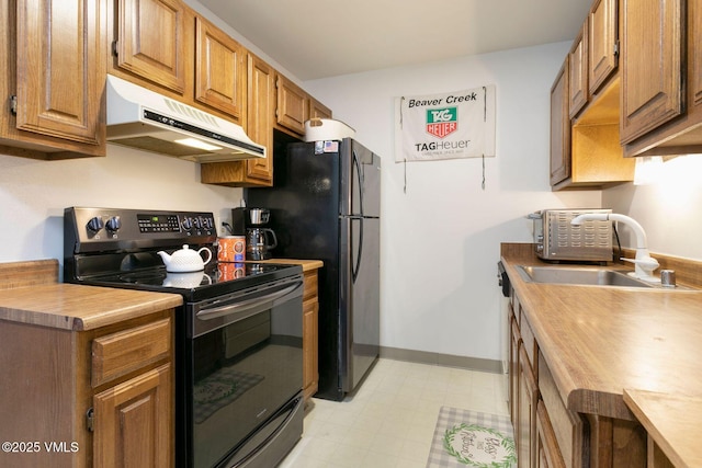 kitchen featuring light floors, electric range, brown cabinetry, a sink, and under cabinet range hood