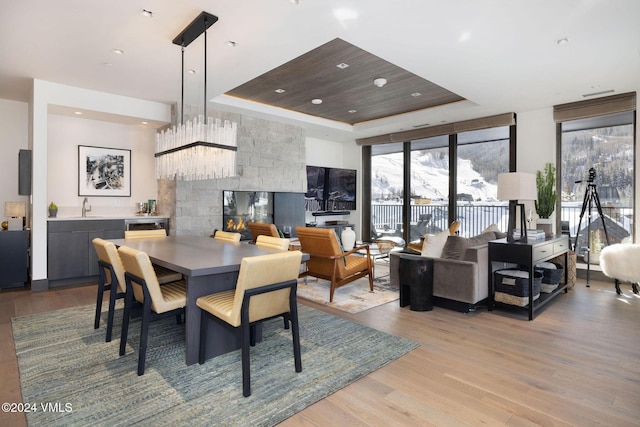 dining room with a raised ceiling, floor to ceiling windows, sink, and light hardwood / wood-style floors