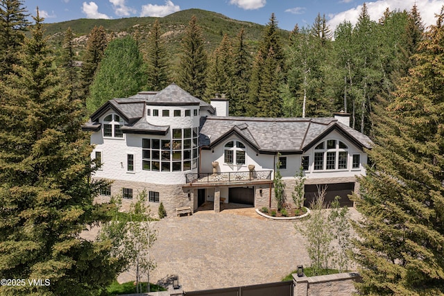 1531 Lake Creek Rd, Edwards, CO 81632 - rear view of house featuring a chimney, an attached garage, a view of trees, driveway, and stone siding