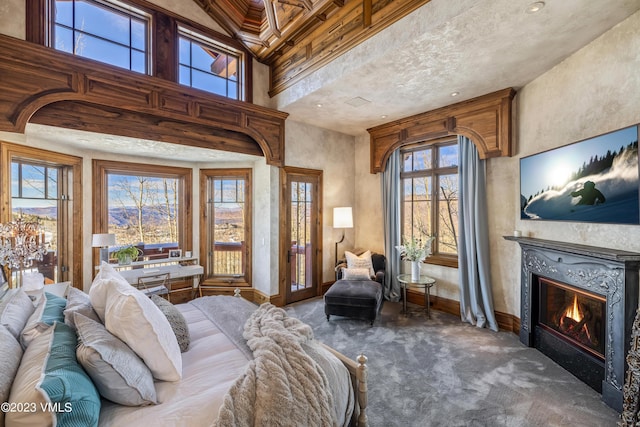 bedroom with a high ceiling, a premium fireplace, access to outside, and dark carpet