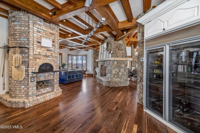 living room featuring coffered ceiling, a large fireplace, dark wood-type flooring, and beam ceiling