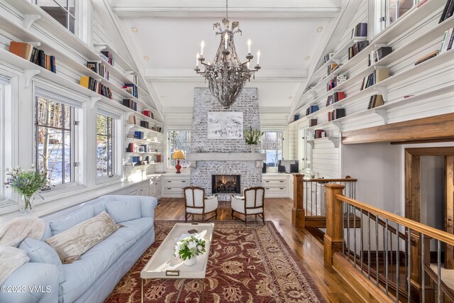 living room with a notable chandelier, wood-type flooring, and beamed ceiling