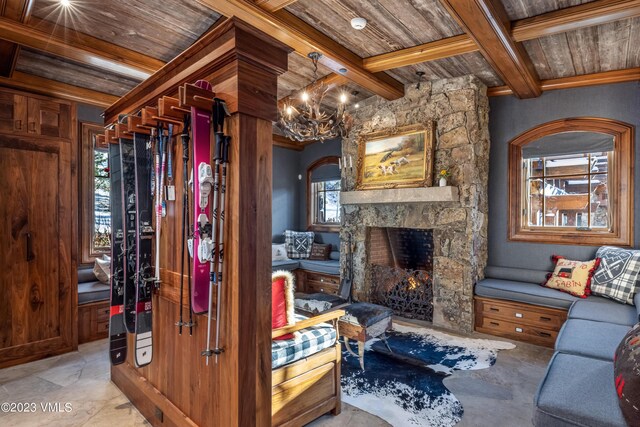 living room featuring wood ceiling, a notable chandelier, a stone fireplace, and beamed ceiling