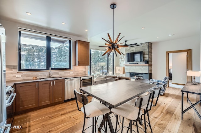 kitchen featuring tasteful backsplash, stainless steel appliances, a sink, and light wood-style flooring