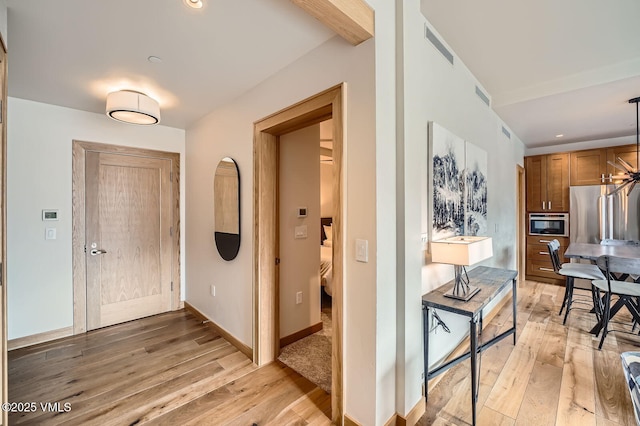 hallway featuring light wood-type flooring, visible vents, baseboards, and recessed lighting