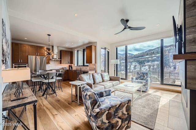 living room featuring light wood-type flooring, a mountain view, recessed lighting, and ceiling fan with notable chandelier