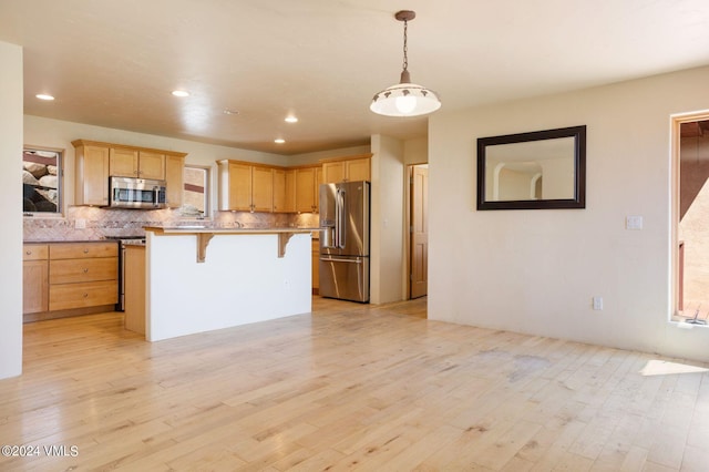 4765 Wildridge Rd, Avon, CO 81620 - kitchen with light wood-style floors, light brown cabinets, stainless steel appliances, and a kitchen bar
