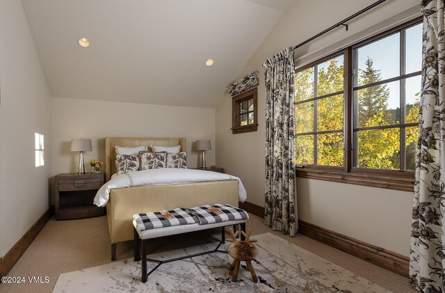 bedroom featuring multiple windows, vaulted ceiling, and light colored carpet