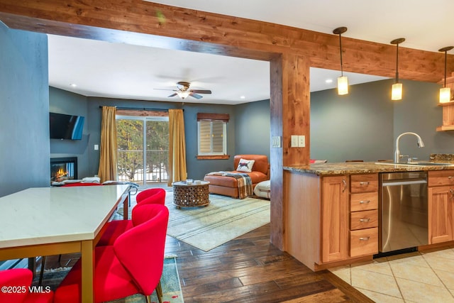 kitchen featuring sink, stainless steel dishwasher, pendant lighting, ceiling fan, and light hardwood / wood-style floors