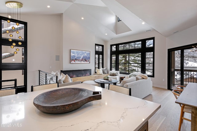 dining room with light wood-style floors, recessed lighting, visible vents, and a glass covered fireplace