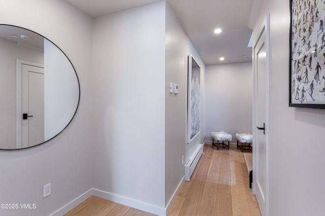 hall with baseboards, light wood finished floors, baseboard heating, and recessed lighting