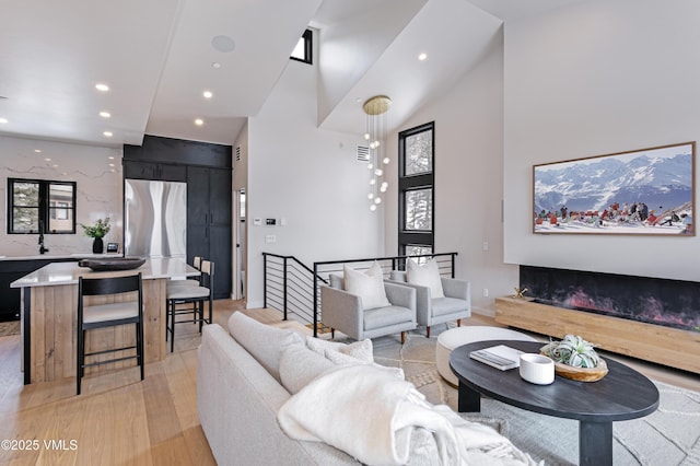 living area featuring light wood-style floors, recessed lighting, and a towering ceiling