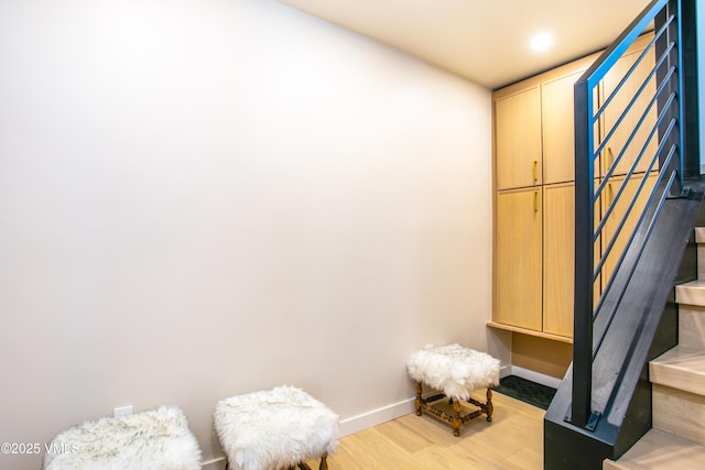 interior space featuring light wood-style flooring, baseboards, and stairs