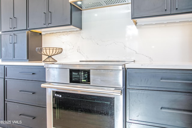 kitchen with tasteful backsplash, exhaust hood, and gray cabinetry