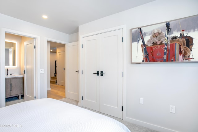 carpeted bedroom with recessed lighting, a sink, baseboards, a closet, and ensuite bath