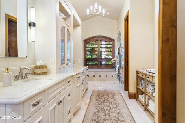 bathroom featuring lofted ceiling, tile patterned flooring, a chandelier, vanity, and a bathing tub