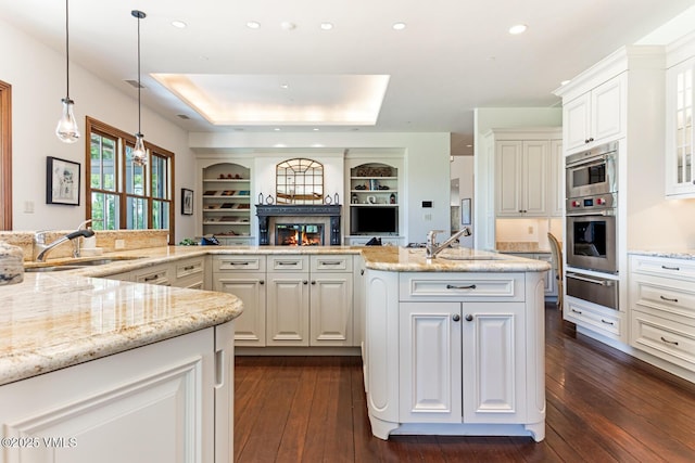 46 Jasmine, Avon, CO 81620 - kitchen featuring a warming drawer, a glass covered fireplace, dark wood-style flooring, light stone countertops, and white cabinets