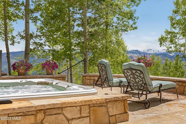 view of patio with a hot tub and a mountain view