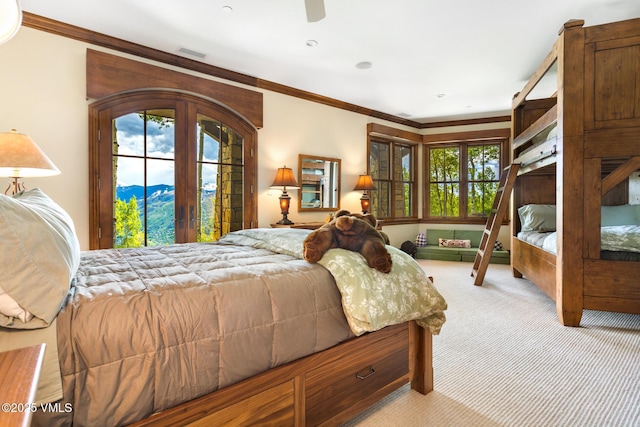 bedroom featuring light carpet, a mountain view, crown molding, and french doors