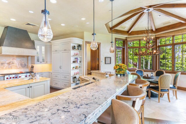 kitchen with pendant lighting, sink, white cabinets, custom exhaust hood, and stainless steel gas stovetop