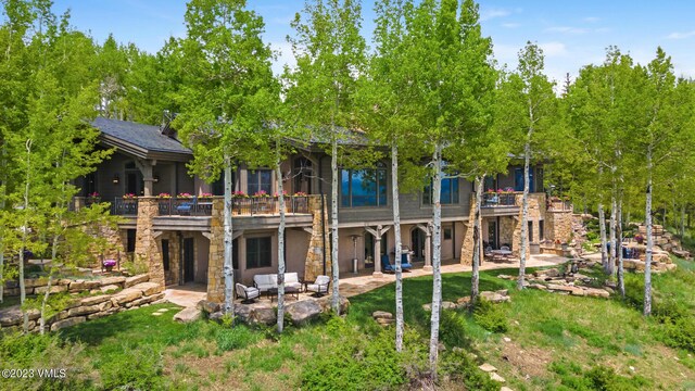 back of property with an outdoor living space, a patio, and a balcony