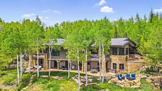 back of house featuring a sunroom, a patio area, and an outdoor stone fireplace