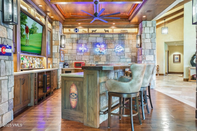 bar with hardwood / wood-style floors, ornamental molding, and ceiling fan