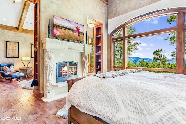 bedroom featuring hardwood / wood-style flooring, beamed ceiling, and a towering ceiling