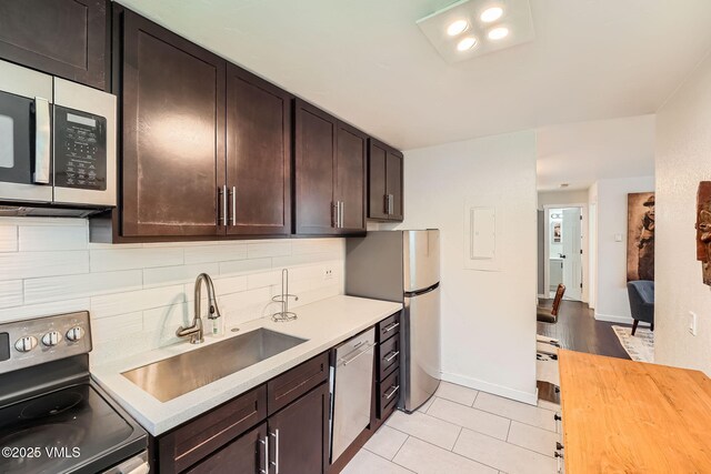 871 W Beaver Creek Blvd Unit A9, Avon, CO 81620 - kitchen featuring stainless steel appliances, a sink, dark brown cabinets, tasteful backsplash, and light tile patterned floors