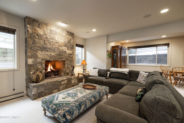 carpeted living room featuring a baseboard heating unit and a stone fireplace