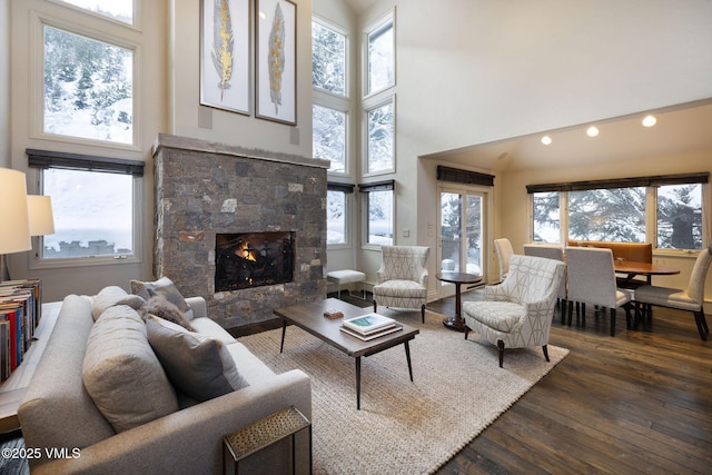 living room with dark hardwood / wood-style flooring, a towering ceiling, and a fireplace