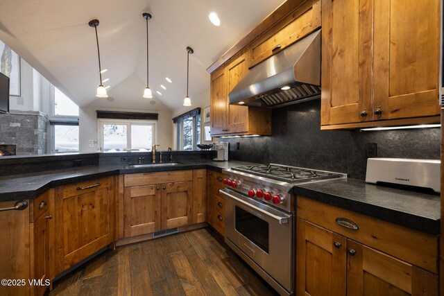 kitchen featuring wall chimney exhaust hood, sink, hanging light fixtures, stainless steel range, and dark hardwood / wood-style floors