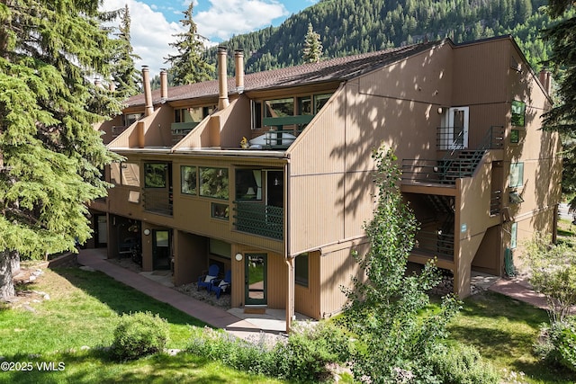 3931 Bighorn Rd Unit 5-E, Vail, CO 81657 - rear view of house featuring a balcony, a lawn, a patio, and a mountain view