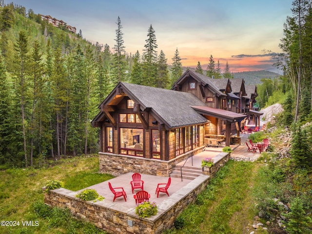 back house at dusk featuring an outdoor fire pit and a patio area