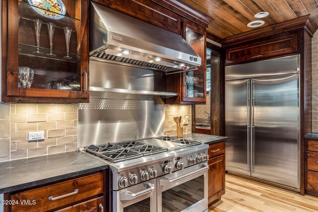 kitchen featuring decorative backsplash, dark stone counters, stainless steel appliances, wooden ceiling, and light hardwood / wood-style flooring