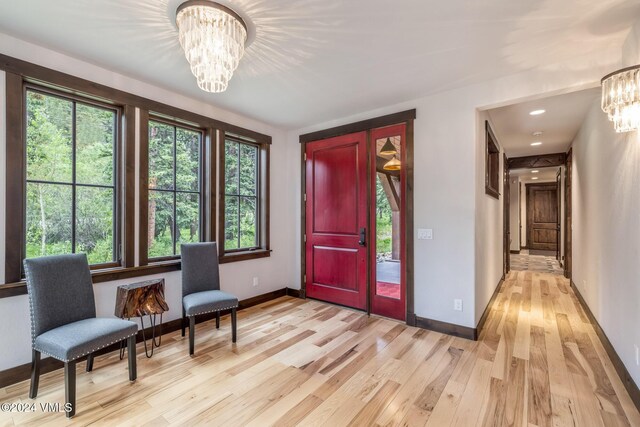 living area with an inviting chandelier and light hardwood / wood-style flooring