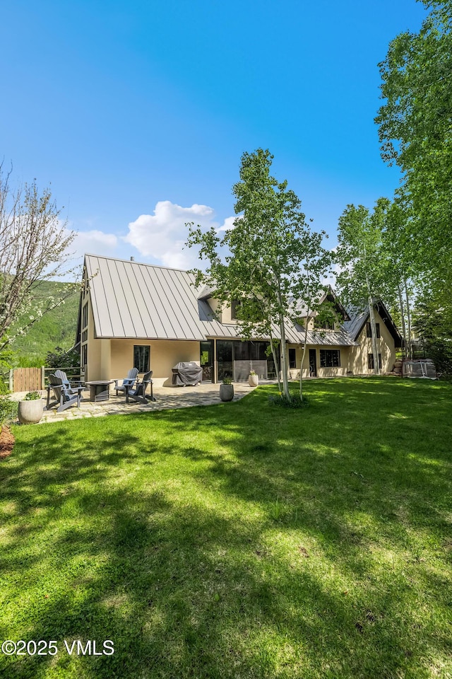2036 Vermont Rd, Vail, CO 81657 - rear view of property featuring a standing seam roof, stucco siding, a patio area, metal roof, and a lawn