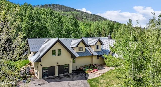 2036 Vermont Rd, Vail, CO 81657 - view of front of property featuring stucco siding, a forest view, a standing seam roof, and a garage