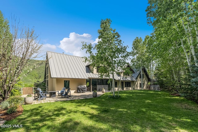 2036 Vermont Rd, Vail, CO 81657 - back of house with stucco siding, a patio area, a yard, metal roof, and a standing seam roof