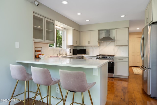 50 Hereford Rd, Edwards, CO 81632 - kitchen featuring wall chimney range hood, stainless steel appliances, a peninsula, tasteful backsplash, and recessed lighting