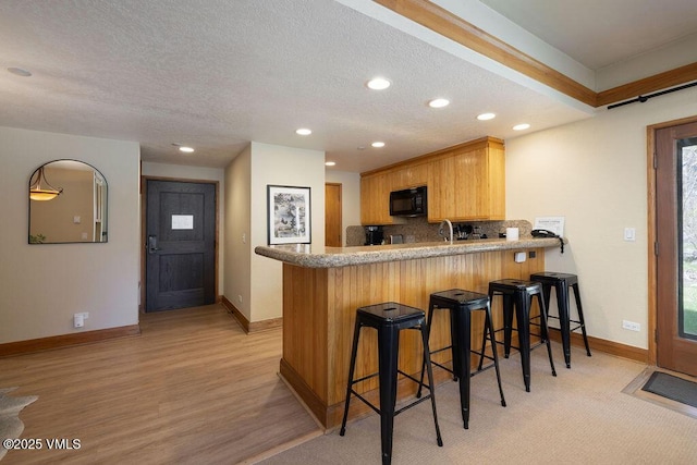 120 Offerson Rd Unit 3002, Beaver Creek, CO 81620 - kitchen featuring black microwave, recessed lighting, a peninsula, baseboards, and light wood finished floors