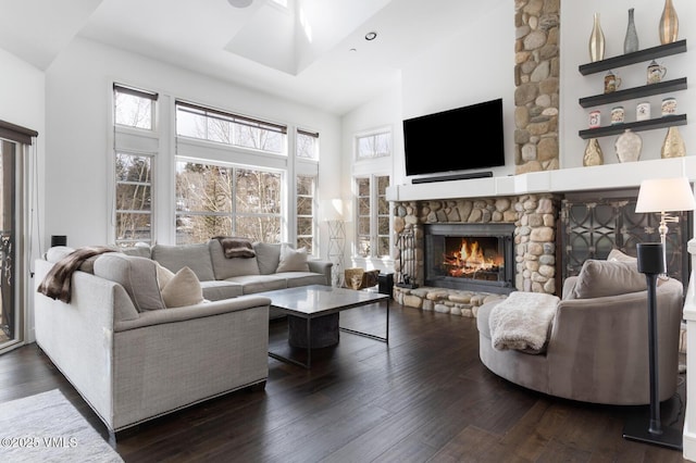 living room with a stone fireplace, dark wood-style floors, and high vaulted ceiling