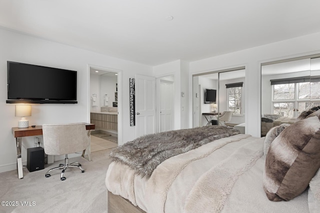 carpeted bedroom featuring connected bathroom, baseboards, and two closets