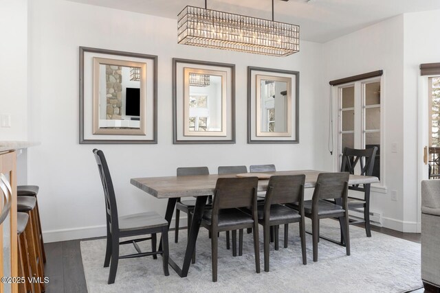 dining area with a chandelier, baseboards, and wood finished floors