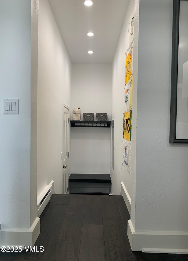 corridor with recessed lighting, a baseboard heating unit, and wood finished floors