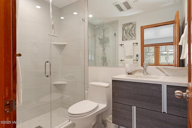 bathroom featuring visible vents, vanity, toilet, and a shower stall