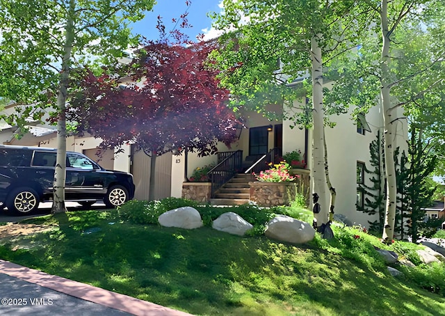 view of property hidden behind natural elements with stucco siding