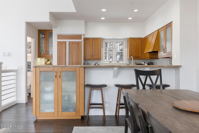 kitchen featuring brown cabinets, a breakfast bar, and glass insert cabinets