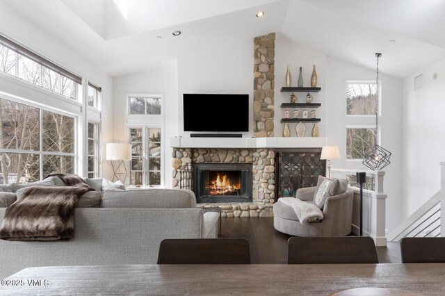 living area featuring a fireplace, visible vents, and high vaulted ceiling